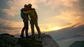 Wide handheld shot of a male mountaineer extending his hand to his...