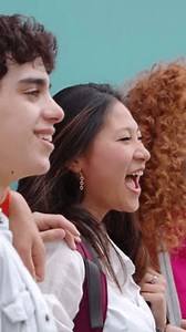 Side view of multiethnic group of college student friends posing over blue background. Millennial people standing together at college campus. Youth community concept. Vertical 9:16 screen video.