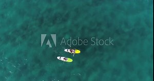 Close-up aerial view of young pretty girls paddling in the sea on their stand up paddle boards (SUP)