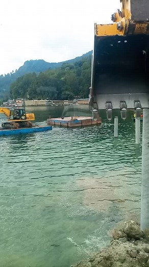 Excavator in Action: Digging in Water with Scenic View