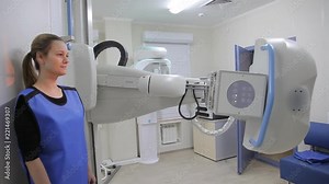 A beautiful woman standing patient is undergoing an examination of the body using an x-ray device. The X-ray device is moving around it. Medical technology.4K