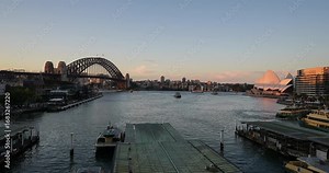 Sydney, Australia - August 23 2025: Time lapse of the sunset over Sydney harbor and Circular Quay ferry terminal and the Harbor bridge.