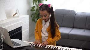 Little girl watching online lesson tutorial how to learn a synthesizer
