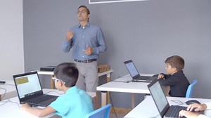 Premium stock video - Computer science teacher explaining lesson to children