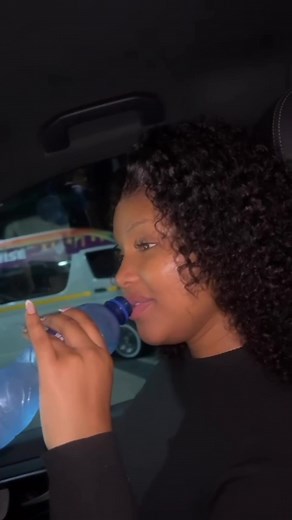 Curly-Haired Person Using Smartphone in Modern Vehicle