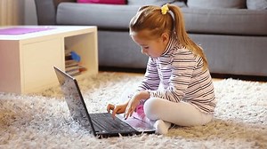 Little girl with laptop at home. Smart preschool child using computer.