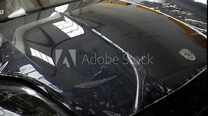 Close up of paint protection film installation on front bumper of modern luxury car. PPF is polyurethane film applied to car surface to protect the paint from stone chips, bug splatter, and abrasion.