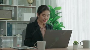Enthusiastic businesswoman working and typing laptop in the office. Beautiful young office lady sitting at her desk and working with laptop.