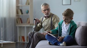 Angry grandpa scolding grandson for playing video game on tablet, generation gap