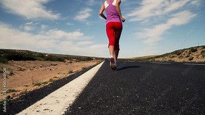 Beautiful young woman running on the road, slow motion