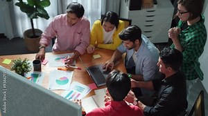 Group of diverse people brainstorming marketing plan by using sticky note while clapping hands. Top view discussing and talking about stock market investment while working on laptop. Convocation.