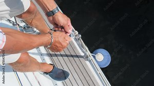 Seasoned yachtsman unties mooring ball preparing vessel for docking. Sailor engages in mooring process for secure stay in harbor