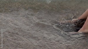 woman girl legs walking on beach seashore ocean sands.female playing with feet barefoot sole in water water sitting on big rock coast line close up 4k real time video summer vacation trip travel
