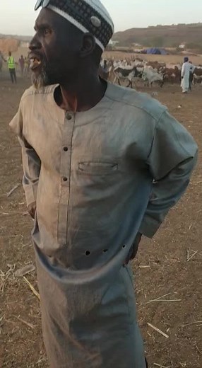 Man Explains Goat Herding Techniques in Rural Setting