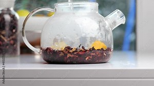 Red tea with lemon in glass pot, Red Chinese hibiscus rosa healthy tea pouring in water. Slow motion