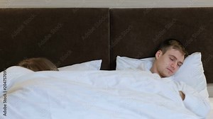 blanket pulling. couple sleeping in bed and fighting for the duvet. woman and man steeling the cover from each other