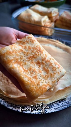 Clătite cu brânză și stafide la cuptor O rețetă delicioasă și aromată, perfectă pentru un desert de familie. Ingrediente Pentru aluatul de clătite: - 3 ouă - Un praf de sare - 20 ml ulei - 10 g zahăr vanilat - Coaja rasă de la 1 portocală - 1 cană mare (300 ml) lapte - 1 cană mare (300 ml) apă minerală - 2 căni mari (300 ml fiecare) de făină Notă: Folosește aceeași cană pentru a măsura laptele, apa minerală și făina. Pentru umplutură: - 500 g brânză de vacă - 2 ouă - 20 g zahăr vanilat - 1 lingu