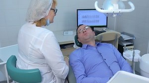Dentist woman makes preventive examination of man sitting in dental chair. Consultation of man by doctor stomatologist in dentistry stomatology clinic. Hygiene and health of the oral cavity.