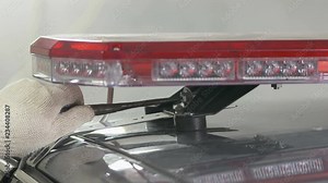 Emergency vehicle lighting installation. Mounting police red blue emergency LED light bar on top of the car.