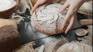 Bread background - various types of bread are served on the table, a woman puts a ready-made loaf of fresh cereal bread on the table
