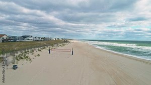 Low aerial view moving backwards over empty Long Beach Island NJ coast, 4K
