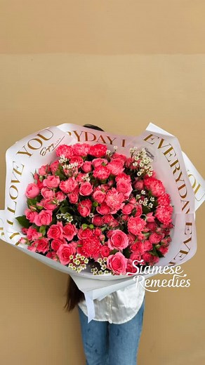 A bold and radiant bouquet of fuchsia spray roses, carnations, and...
