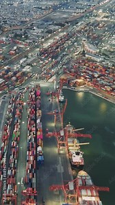 Drone films the seaport at sunset, capturing the busy container terminal. Containers are stacked and ready for shipping. The video showcases the efficiency and scale of container handling at seaport