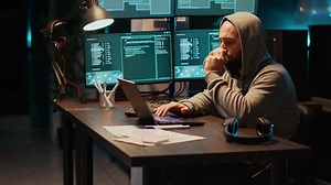 Hacker programmer coding system late at night, using virus to produce computer malware and error. Data developer stealing information from software app, working with multiple monitors.