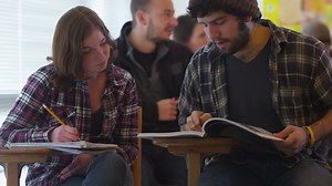 Download College students sitting in classroom studying for free