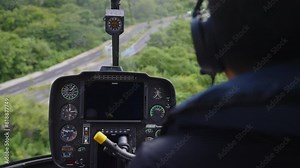 Cockpit view from a helicopter with pilot, showcasing instruments and scenery outside. Aircraft dashboard with indicators and navigation equipment. Flying inside cabin
