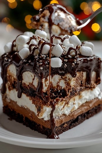 Hot Chocolate Lasagna! Layers of rich OREO crust, creamy chocolate cream cheese, fluffy whipped topping, and a decadent chocolate ganache, all topped with mini marshmallows. It's like a cozy mug of hot chocolate in dessert form! Perfect for holiday gatherings or a comforting treat. #HotChocolateLasagna #ChocolateDessert #NoBakeDessert #HolidayDessert #WinterDessert #ChocolateLover #DessertRecipe #EasyDessert #ComfortFood #SweetTreats #OREOCrust #MarshmallowTopping #HomemadeDessert #Foodie #Delic