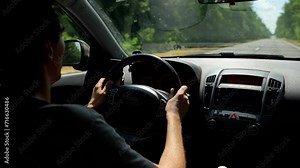 Young man in glasses driving a car alone on empty road in cloudy weather. Young guy traveling by car alone on the road in the forrest. Self driving car trip. High quality 4k footage