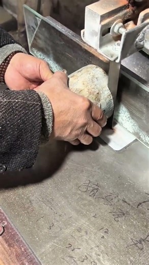 cutting a thick piece of wood with a vertical band saw machine in a workshop