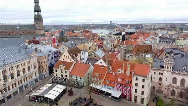 Riga, Latvia's skyline features St. Peter's Church spire, colorful buildings, and red tiled roofs. The Daugava River and National Library are visible.