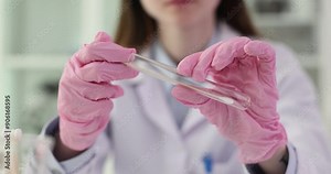 Woman scientist inserts cotton swab into test tube. Professional researcher rotates cotton swab to collect sample for analysis slow motion