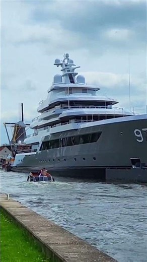 A huge mega yacht on a narrow Dutch river is accompanied by vintage tugboats. VALOR Pleasure Craft