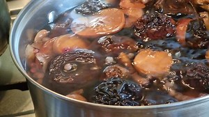 Download Preparation of dried fruit compote in a saucepan. Slow bubbling of boiling water and red currant berries, dried apples and pears. Stewed fruit. for free
