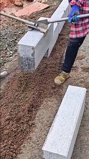 installing and aligning concrete curb blocks using a metal lever tool by workers at the construction