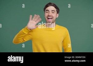 Welcoming American young 20s aged man Waving Hand - Hello, Hi, salute, chao. Greetings on green studio. High quality 4k footage Stock Video Footage - Alamy