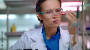 Woman chemist doing chemical test in chemistry laboratory. Closeup of female chemist working with chemical liquid in test tube. Chemistry scientist mixing chemical liquid in flask in chemical lab