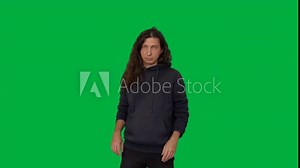 A man with long hair in a black sweatshirt makes expressive hand gestures towards the camera against a green screen. This footage is perfect for compositing or adding visual effects.