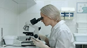 Scientist working with microscopes and smartphone in chemical lab