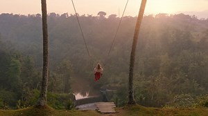 Slow motion woman swinging over tropical rainforest at sunrise travel girl sitting on swing with scenic view enjoying freedom on vacation having fun holiday lifestyle | Premium Stock Video Footage