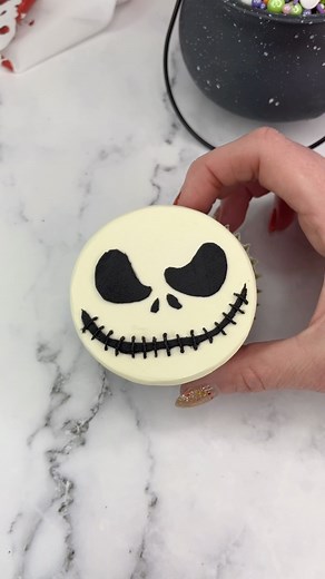 Rachel Lindsay on Instagram: "Jack Skellington cupcakes 🤍🖤 🤍 The Nightmare before Christmas cupcakes 🖤 Which character should I make next? 🤍 Use a large round piping tip (ateco 809) to add white buttercream onto the cupcakes. 🖤 Press the buttercream down onto parchment paper to achieve a flat surface. 🤍 Freeze the cupcake for 15 minutes. 🖤 Remove the parchment paper and attach your stencil to the top. I made the stencil using a square of parchment paper and a sharp blade. 🤍 Apply a thin