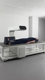Vertical - Man doing full body DEXA scan in a modern medical clinic.