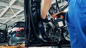 Mechanic is using an electric screwdriver to assemble a car door