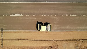 A dirt roller compacts the sand before laying a new asphalt surface, aerial view. Road construction works.