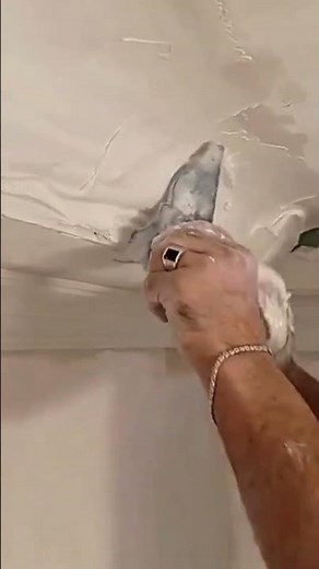 Applying plaster and using a template tool to create decorative crown molding on the room ceiling