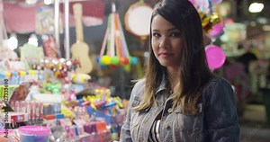Laughing young adult woman with happy expression standing in front of candy table at night Stock Video