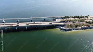 Aerial Drone Trucking Shot Over Blue Bay Water and Palm Trees Towards a Bridge Traffic and Skyline in the Distance. Late Afternoon and Palm Trees are Silhouetted. Clearwater Memorial Causeway FL